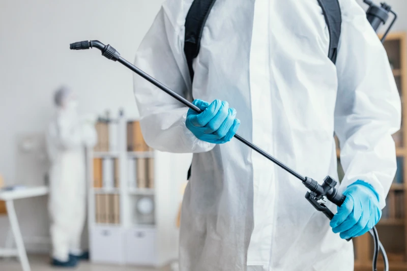 Person disinfecting-dangerous area while wearing protective suit